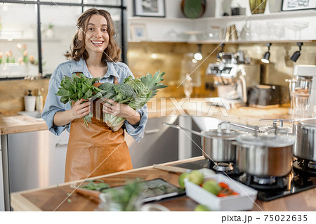 Woman with fresh green vegetables on the kitchen 75022635