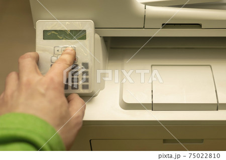 the hand of a person, an office worker, presses the buttons on the control panel of a printer, copier, or multifunction device the hand of a person, an office worker, presses the buttons on the control panel of a printer, copier, or multifunction device 75022810