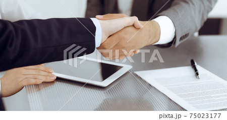 Handshake as successful negotiation ending, close-up. Unknown business people shaking hands after contract signing in modern office 75023177