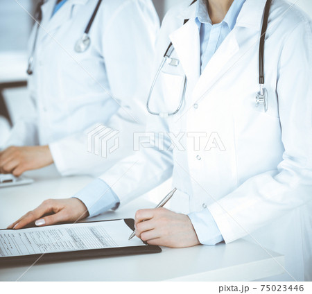 Unknown two women-doctors working at clinic reception desk, close-up. Healthcare and data in medicine Unknown two women-doctors working at clinic reception desk, close-up. Healthcare and data in medicine 75023446