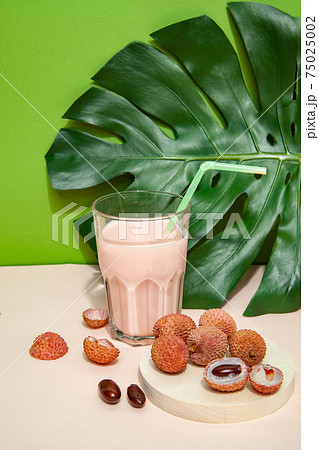 Fresh smoothie and lychee fruits on pink table 75025002