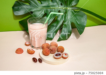 Fresh smoothie and lychee fruits on pink table 75025004
