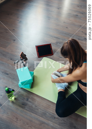 Young woman practicing yoga, is engaged with the teacher online. Young woman practicing yoga, is engaged with the teacher online. 75026069