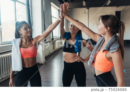 Women giving five each other after having a great workout in gym. 75026080