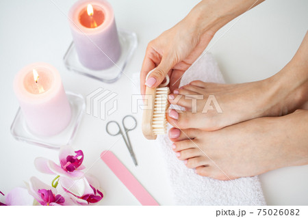 Cozy home spa, young woman doing pedicure on her feet nails. 75026082