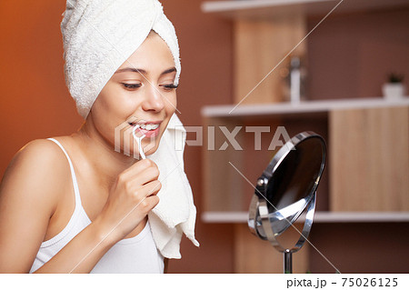 Portrait of beautiful woman cleaning teeth with dental floss Portrait of beautiful woman cleaning teeth with dental floss 75026125