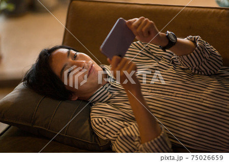 ソファに寝転んでスマホを見る男性 ソファに寝転んでスマホを見る男性 75026659