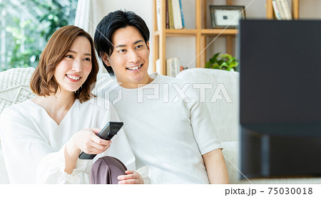 リビングでテレビを見る若い夫婦 リビングでテレビを見る若い夫婦 75030018