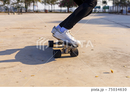 Close-up and motion movement Asian women surf skate or skateboard outdoors on beautiful morning. Happy young women play surf skate at park on morning time. Close up Asian women leg wear sneaker paly Close-up and motion movement Asian women surf skate or skateboard outdoors on beautiful morning. Happy young women play surf skate at park on morning time. Close up Asian women leg wear sneaker paly 75034630