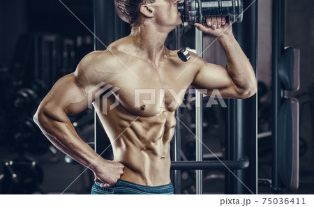 Bodybuilder drinking water after fitness workout. 75036411