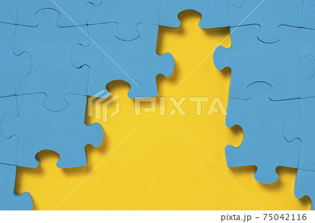 Unfinished blue jigsaw puzzle on yellow background with copy space 75042116