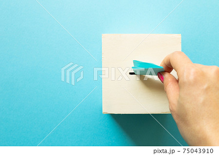 Hand putting voting paper in Ballot box on blue background. top view, copy space Hand putting voting paper in Ballot box on blue background. top view, copy space 75043910