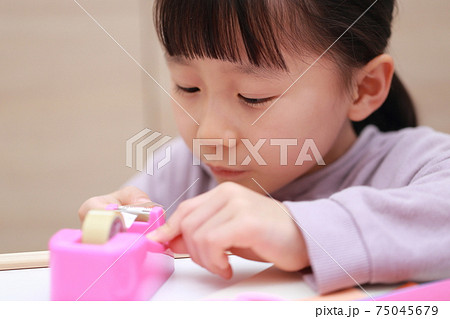 セロハンテープをカットして工作する女の子 75045679