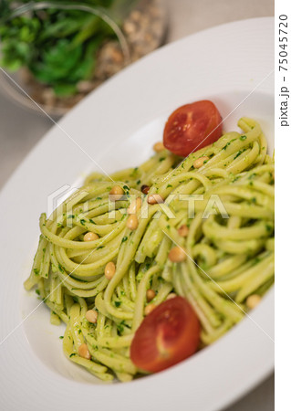 green spinach spaghetti with cheese and tomato on wooden table 75045720