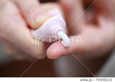 塗り薬を押し出す女性の指 75048232