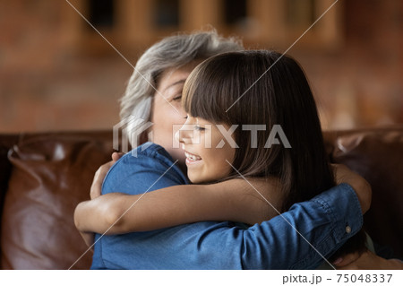 Happy small girl hug mature grandmother at home 75048337