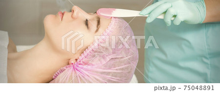 Hand applying alginate mask on face 75048891
