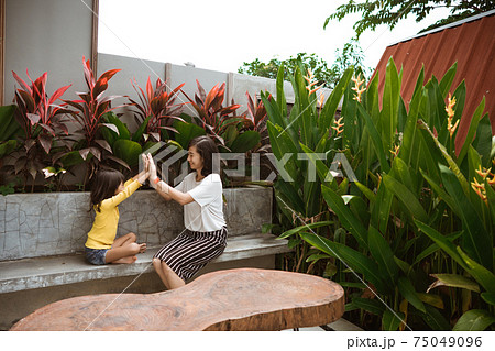 Cute little girl assisting her mother playing and have fun in a backyard. Cute little girl assisting her mother playing and have fun in a backyard. 75049096
