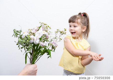 a man's hand holds out a bouquet of white flowers to a cute little girl a man's hand holds out a bouquet of white flowers to a cute little girl 75050300