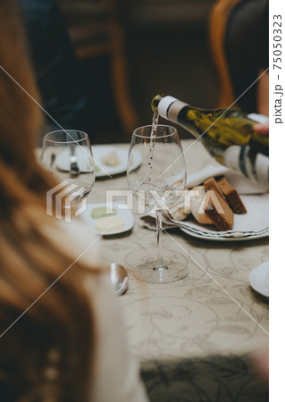 Pouring red wine into the glass against wooden background Pouring red wine into the glass against wooden background 75050323