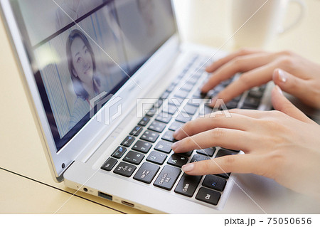 リビングでオンラインミーティングをする女性の手元 75050656