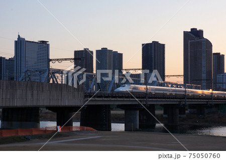 夕暮れ時に多摩川を渡る新幹線と武蔵小杉のビル群の写真素材