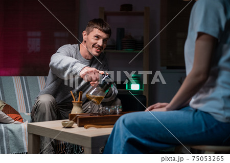 A man and a woman celebrate the anniversary of their acquaintance in a cozy cafe and hold a tea ceremony at the table. They are happy and smiling. 75053265