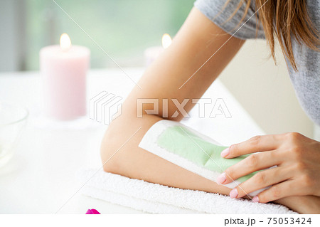 Woman doing hair removal on their hands at home in the bathroom 75053424