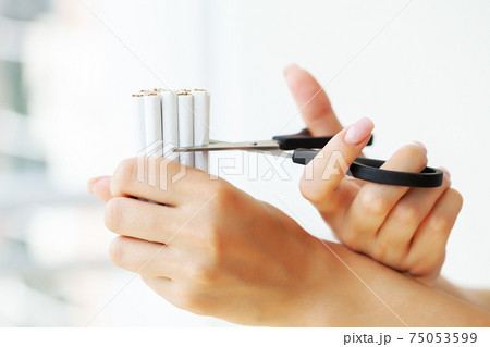 Stop smoking, woman cuts a cigarette with scissors 75053599