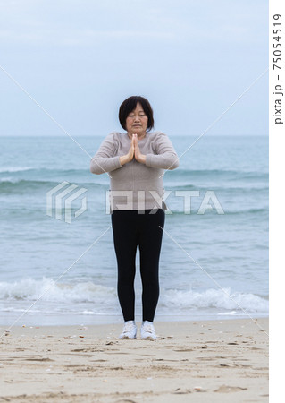 Mature woman practicing meditation near the sea Mature woman practicing meditation near the sea 75054519