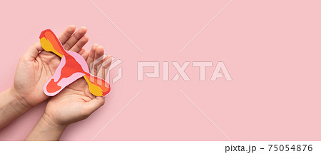 Female reproductive health concept. Woman hand holding uterus shape made frome paper on pink background. Awareness of uterus illness such as endometriosis, PCOS, STDs or gynecologic cancer. 75054876