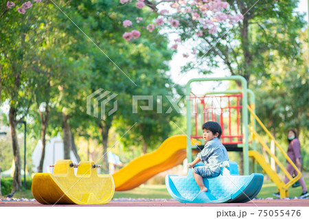 Funny cute happy baby playing rocking horse on the flower tree playground. 75055476