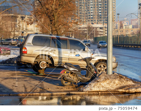Changing a wheel on an SUV against the background of a city street in blur. Changing a wheel on an SUV against the background of a city street in blur. 75059474