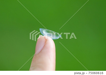 Transparent contact lens on finger tip on blurred green summer nature background Transparent contact lens on finger tip on blurred green summer nature background 75060616