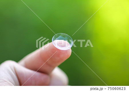 Transparent contact lens on finger tip on blurred green summer nature background Transparent contact lens on finger tip on blurred green summer nature background 75060623