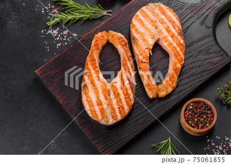 Fresh cooked delicious salmon steak with spices and herbs baked on a grill Fresh cooked delicious salmon steak with spices and herbs baked on a grill 75061855