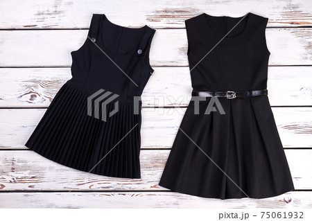 Two black dresses, wooden background. Two black dresses, wooden background. 75061932