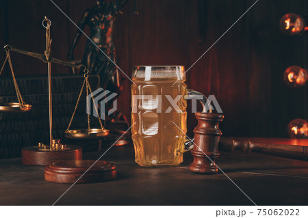 Glass of beer and judge gavel in a courtroom. Alcohol and crimes concept Glass of beer and judge gavel in a courtroom. Alcohol and crimes concept 75062022