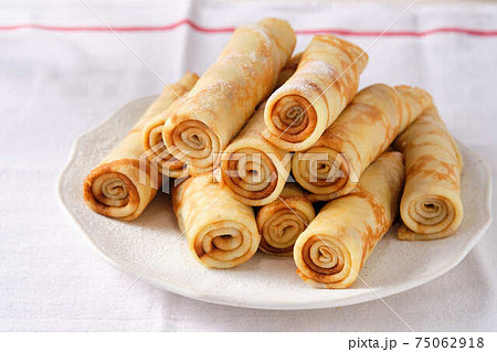 Crepes, thin pancakes with honey and tea on a white plate. Crepes, thin pancakes with honey and tea on a white plate. 75062918