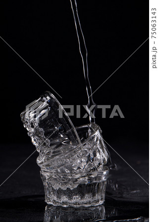 Flowing water is filling stack of three glass cups. Flowing water is filling stack of three glass cups. 75063143