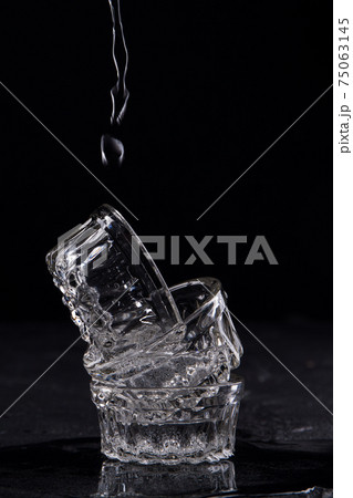 Falling water drops into glassware cups. Falling water drops into glassware cups. 75063145