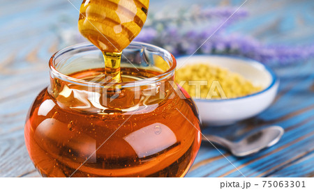 Honey in glass jar with honey dipper over wooden background 75063301