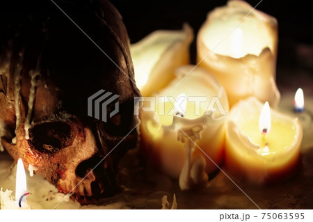 Human skull against dark background in candle light closeup Human skull against dark background in candle light closeup 75063595