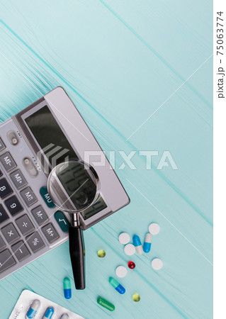 Stethoscope and magnifier over a calculator symbol for health care costs or medical insurance. Stethoscope and magnifier over a calculator symbol for health care costs or medical insurance. 75063774