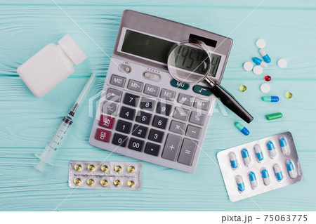 Stethoscope and magnifier over a calculator symbol for health care costs or medical insurance. Stethoscope and magnifier over a calculator symbol for health care costs or medical insurance. 75063775