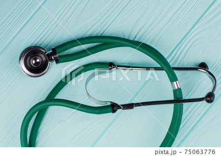 Green stethoscope on turquoise background. Green stethoscope on turquoise background. 75063776