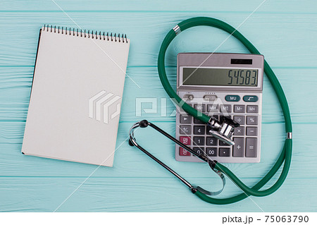 Flat lay medical composition include calculator notepad stethoscope on a blue pastel background. 75063790