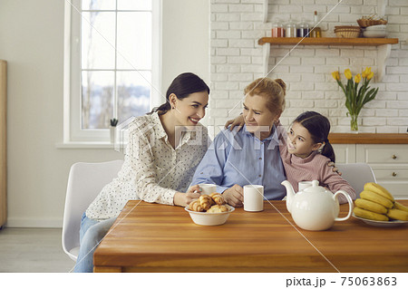 Happy mother, kid and grandmother enjoying good cup of tea and nice chat together 75063863