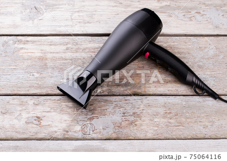 Black hair dryer on wooden background. 75064116
