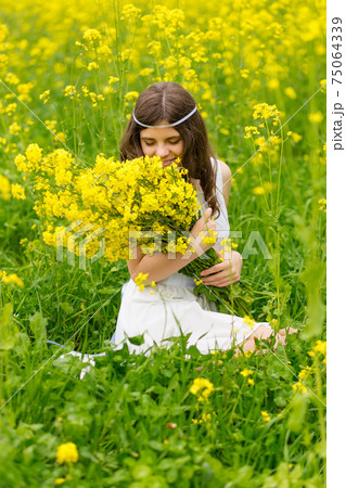 A child in a blooming field with yellow flowers. 75064339